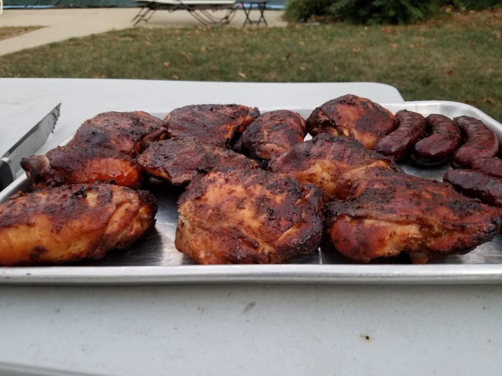Finished smoked chicken thighs on a sheet pan outdoors