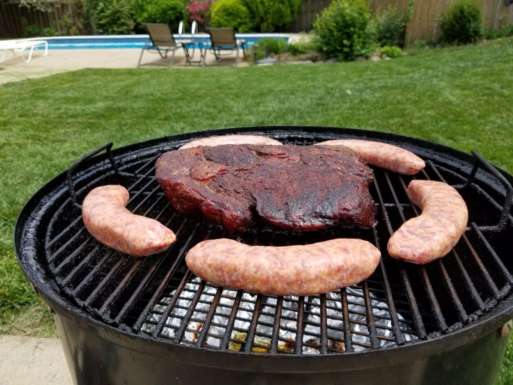 Sausages added to the smoker alongside the chuck roast