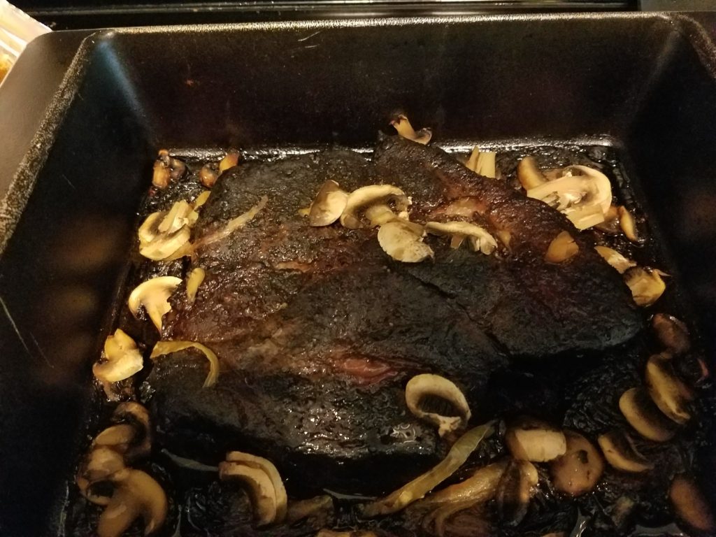 Chuck roast finishing in the oven with onions and mushrooms
