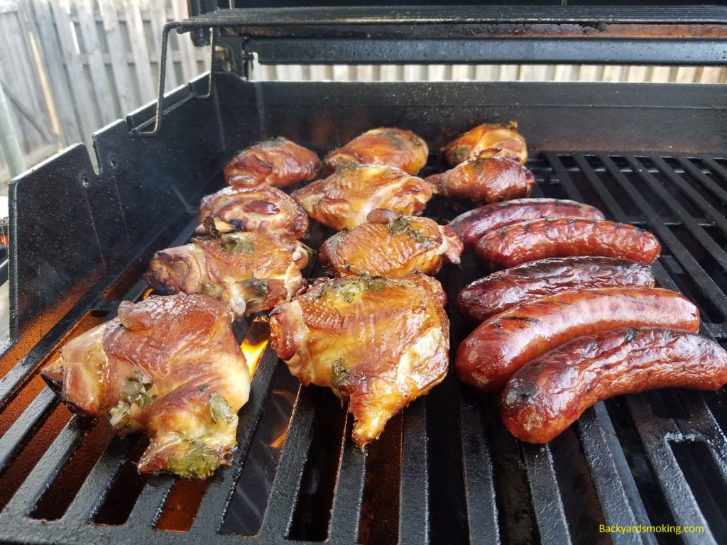 Chicken and sausages finishing on the hot grill to crisp up