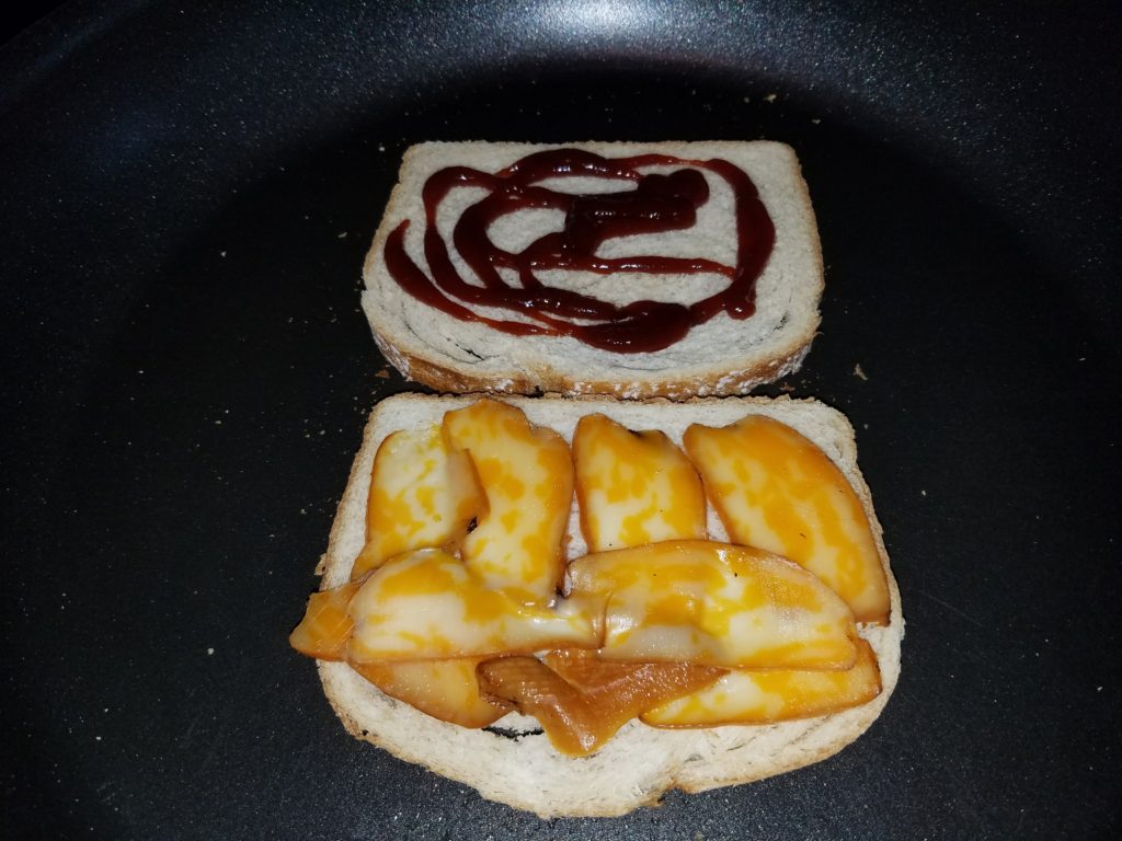 Sourdough halves in the pan, barbecue sauce on one side and smoked Colby Jack melting on the other