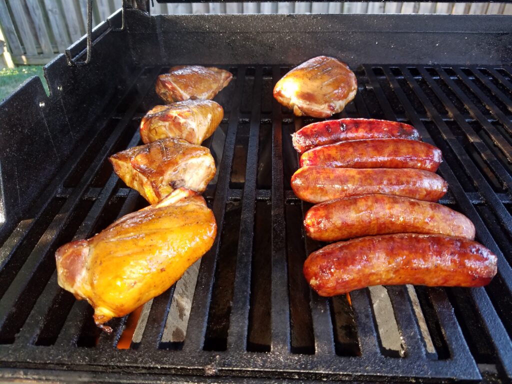 Chicken thighs and sausages on the propane grill grates to finish