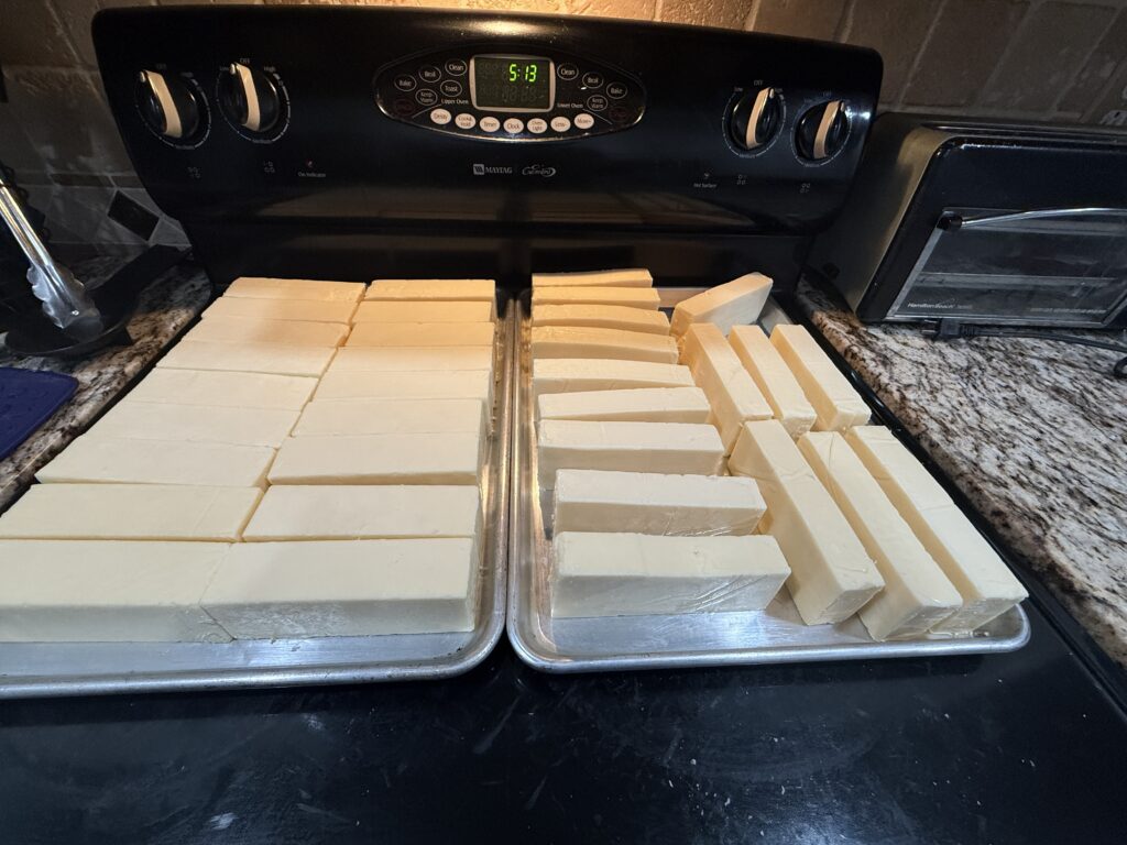 White cheddar sticks arranged on sheet pans before cold smoking