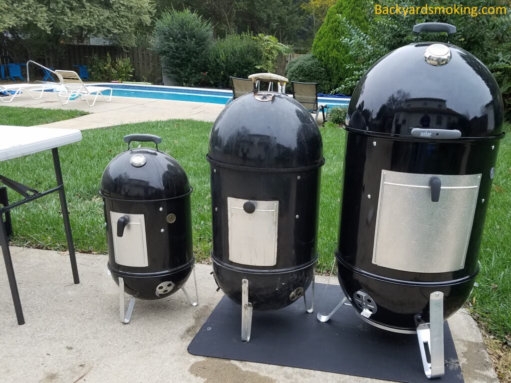 My three Weber Smokey Mountain smokers — 14.5", 18", and 22" — lined up before the garage fire